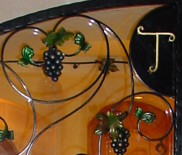 Détail doré du portail forgé, motif vigne